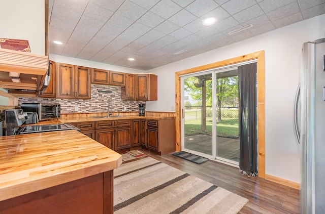 509 8th Ave SE, Isanti, MN 55040 - kitchen with wooden counters, a sink, freestanding refrigerator, light wood finished floors, and tasteful backsplash
