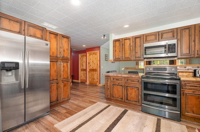 509 8th Ave SE, Isanti, MN 55040 - kitchen featuring stainless steel appliances, brown cabinetry, light wood-type flooring, and recessed lighting
