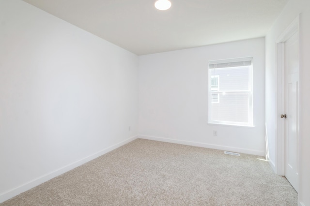 spare room with light carpet and baseboards
