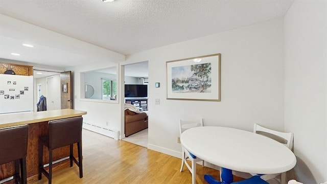 13993 Crosstown Blvd NW, Andover, MN 55304 - dining room with a baseboard heating unit, light wood-style floors, and a textured ceiling