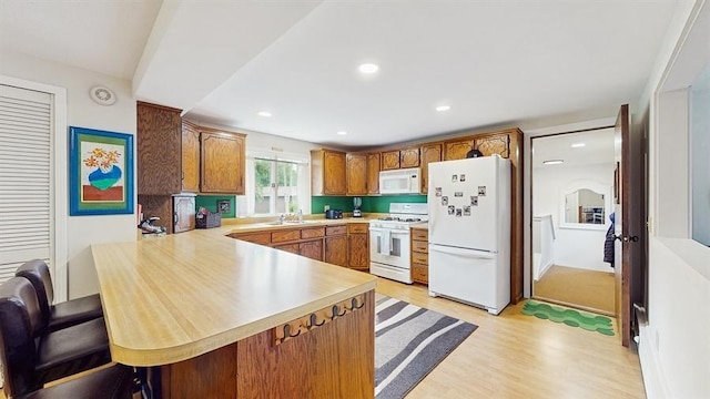 13993 Crosstown Blvd NW, Andover, MN 55304 - kitchen featuring white appliances, a peninsula, light countertops, light wood-style floors, and brown cabinets