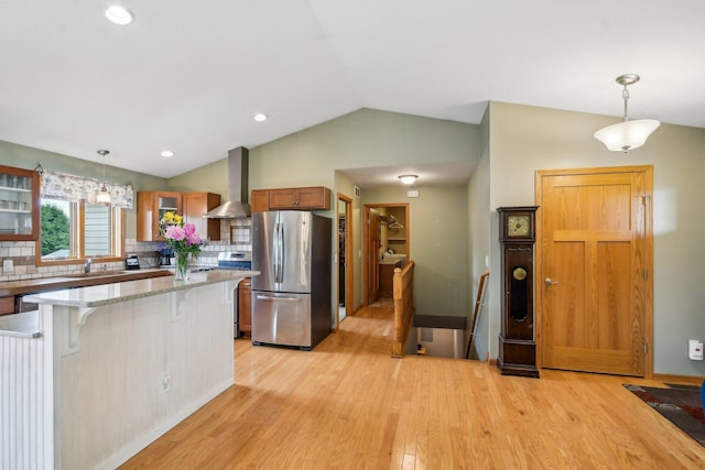 106 Prairie Grass Dr, Osceola, WI 54020 - kitchen with appliances with stainless steel finishes, wall chimney range hood, a breakfast bar, light wood finished floors, and decorative backsplash