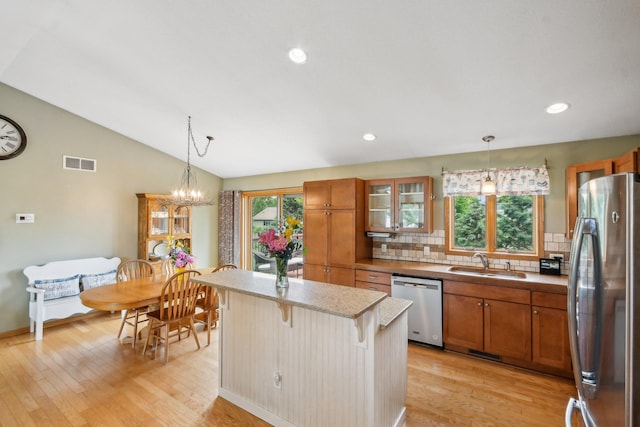 106 Prairie Grass Dr, Osceola, WI 54020 - kitchen featuring stainless steel appliances, brown cabinetry, light wood finished floors, tasteful backsplash, and a breakfast bar