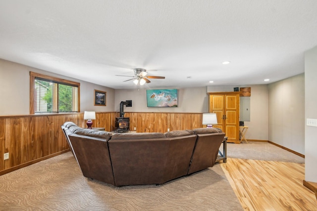 106 Prairie Grass Dr, Osceola, WI 54020 - living area with a wood stove, ceiling fan, light wood-style floors, wooden walls, and electric panel
