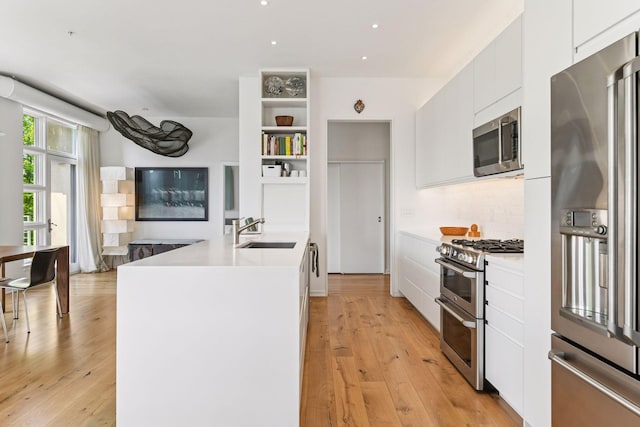 2845 Colfax Ave S Unit W305, Minneapolis, MN 55408 - kitchen with stainless steel appliances, a sink, open shelves, a peninsula, and white cabinetry