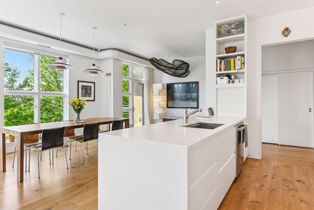 2845 Colfax Ave S Unit W305, Minneapolis, MN 55408 - kitchen featuring a sink, white cabinets, light wood-style floors, decorative light fixtures, and light countertops