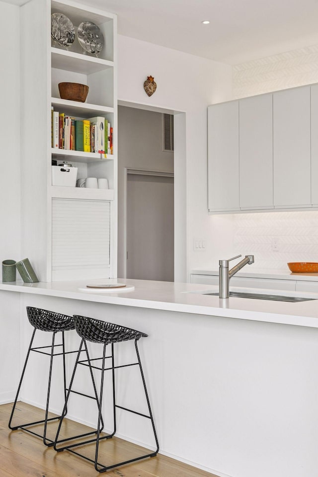 2845 Colfax Ave S Unit W305, Minneapolis, MN 55408 - kitchen featuring a sink, a breakfast bar area, wood finished floors, light countertops, and recessed lighting
