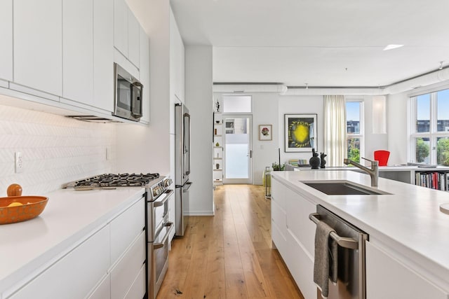 2845 Colfax Ave S Unit W305, Minneapolis, MN 55408 - kitchen featuring appliances with stainless steel finishes, a sink, backsplash, light countertops, and light wood-style flooring