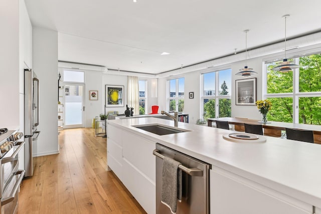 2845 Colfax Ave S Unit W305, Minneapolis, MN 55408 - kitchen with stainless steel appliances, a sink, white cabinets, light countertops, and hanging light fixtures