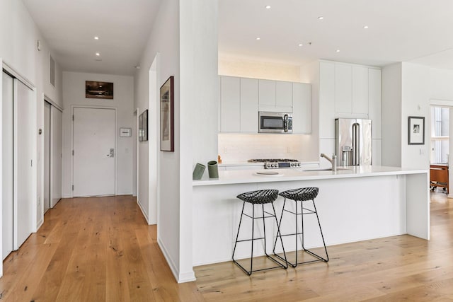 2845 Colfax Ave S Unit W305, Minneapolis, MN 55408 - kitchen with appliances with stainless steel finishes, a sink, a peninsula, light countertops, and light wood-style floors