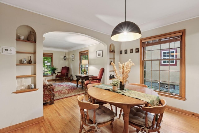 3527 Queen Ave N, Minneapolis, MN 55412 - dining room featuring arched walkways, ornamental molding, light wood-style floors, and built in shelves