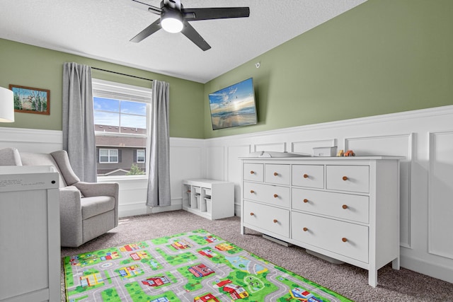 7243 Fall Dr, Lino Lakes, MN 55038 - bedroom with a wainscoted wall, light carpet, a decorative wall, ceiling fan, and a textured ceiling