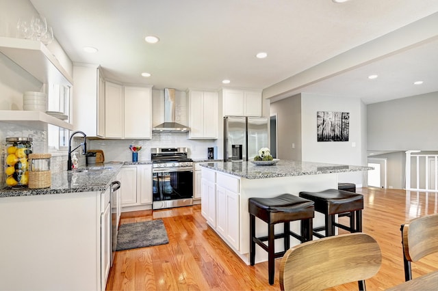 2610 Lake Shore Ave, Little Canada, MN 55117 - kitchen with appliances with stainless steel finishes, wall chimney exhaust hood, a sink, white cabinetry, and recessed lighting