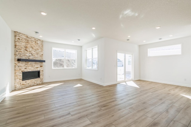 11444 Fieldstone Dr, Rogers, MN 55311 - unfurnished living room featuring light wood-style flooring, plenty of natural light, recessed lighting, a fireplace, and baseboards