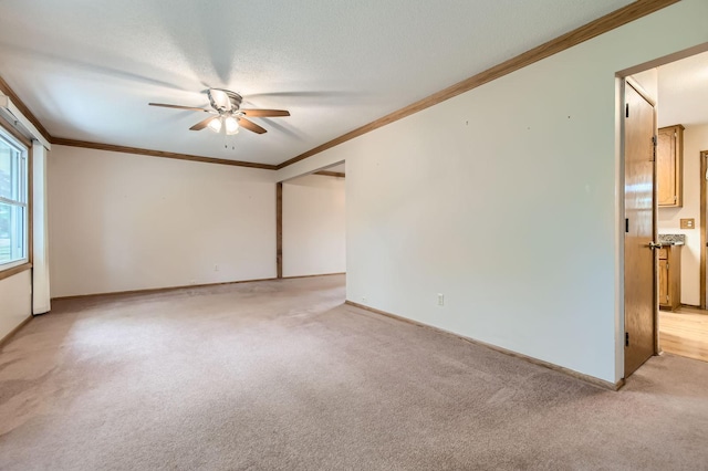 empty room featuring a ceiling fan, light colored carpet, ornamental molding, and baseboards