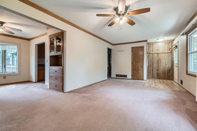 unfurnished living room featuring ceiling fan, light carpet, baseboards, and ornamental molding