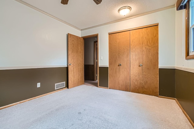 unfurnished bedroom featuring carpet, a closet, a ceiling fan, and a textured ceiling