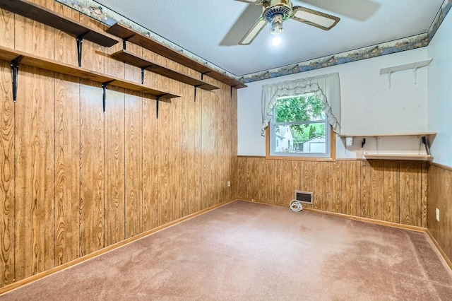 unfurnished room featuring wood walls, a ceiling fan, a wainscoted wall, and carpet flooring