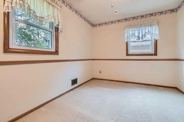unfurnished room with light colored carpet, plenty of natural light, and baseboards