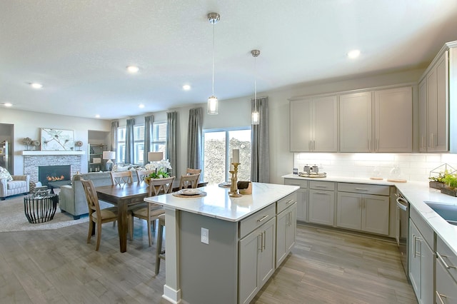 890 Laurel Ct, Chaska, MN 55318 - kitchen with gray cabinetry, backsplash, light wood-style floors, a stone fireplace, and open floor plan