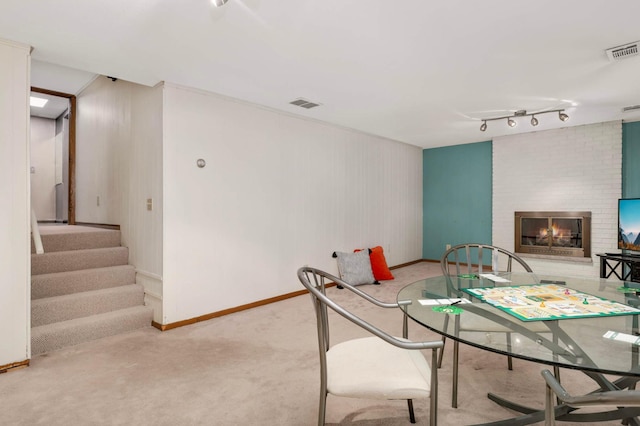 123 Windsor Ct, New Brighton, MN 55112 - carpeted dining area featuring a brick fireplace, baseboards, stairs, and rail lighting