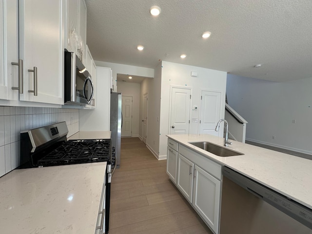 20025 62nd Pl, Corcoran, MN 55340 - kitchen featuring appliances with stainless steel finishes, a sink, white cabinetry, light stone countertops, and a textured ceiling