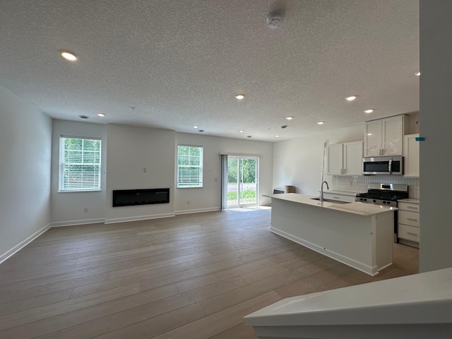 20025 62nd Pl, Corcoran, MN 55340 - kitchen featuring appliances with stainless steel finishes, a textured ceiling, a sink, a kitchen island with sink, and recessed lighting