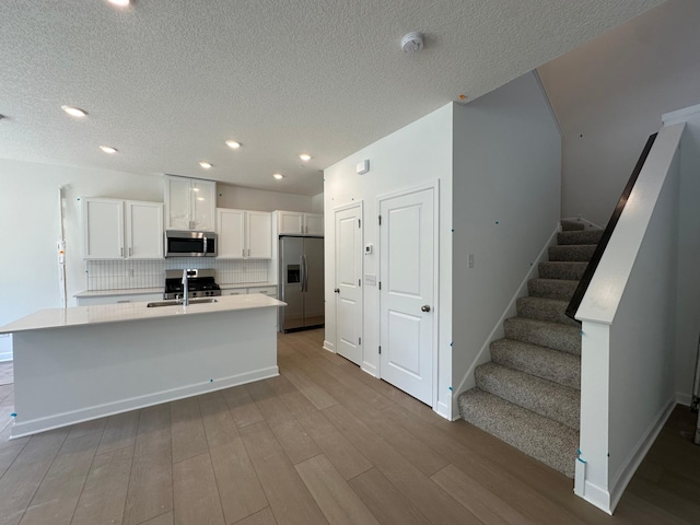 20025 62nd Pl, Corcoran, MN 55340 - kitchen featuring appliances with stainless steel finishes, white cabinetry, wood finished floors, backsplash, and light countertops