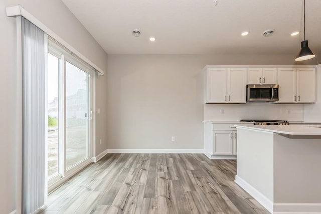 20025 62nd Pl, Corcoran, MN 55340 - kitchen with stainless steel microwave, light wood finished floors, plenty of natural light, white cabinets, and recessed lighting