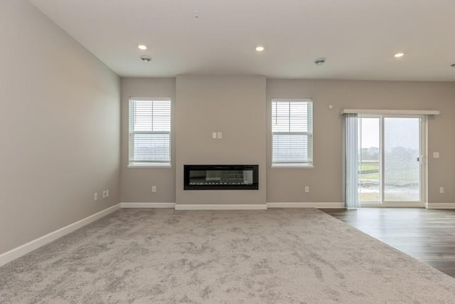 20025 62nd Pl, Corcoran, MN 55340 - unfurnished living room with baseboards, recessed lighting, a glass covered fireplace, wood finished floors, and carpet flooring