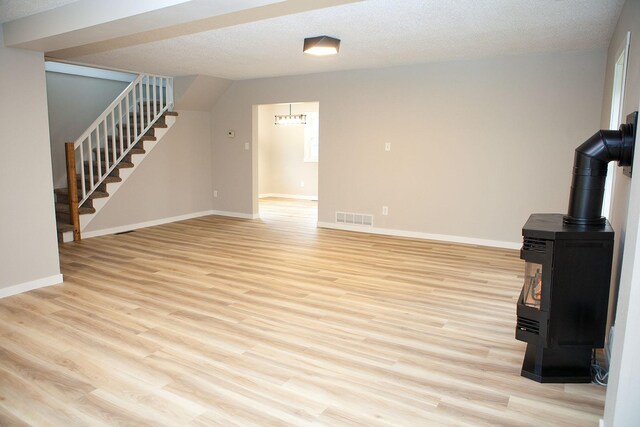 213 Lake Ave, Detroit Lakes, MN 56501 - unfurnished living room with a wood stove, stairs, light wood-style floors, and baseboards
