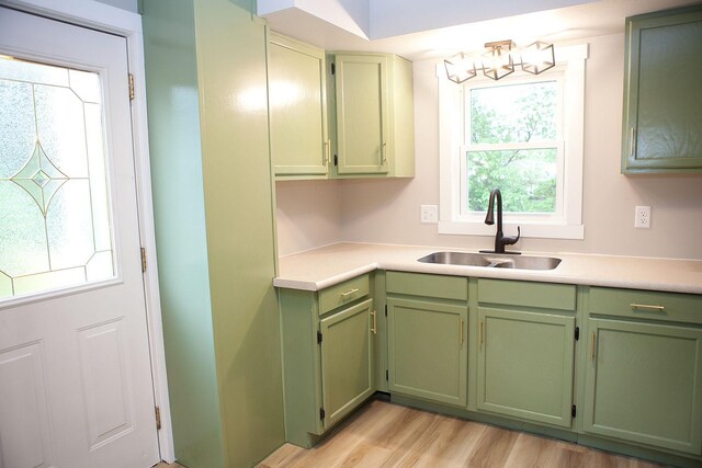 213 Lake Ave, Detroit Lakes, MN 56501 - kitchen with green cabinetry, a sink, light countertops, light wood-type flooring, and a chandelier