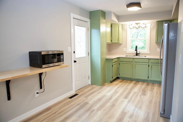 213 Lake Ave, Detroit Lakes, MN 56501 - kitchen with green cabinets, appliances with stainless steel finishes, a sink, light wood-style floors, and light countertops