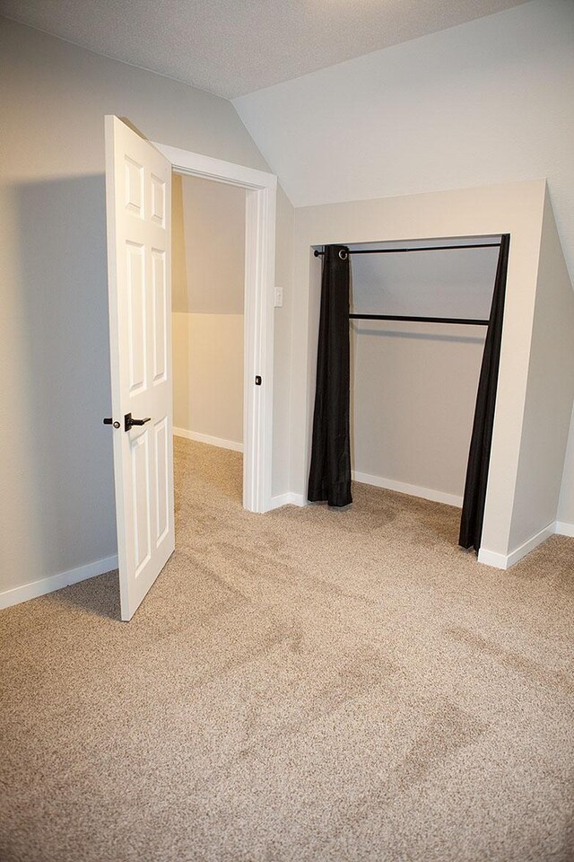 213 Lake Ave, Detroit Lakes, MN 56501 - unfurnished bedroom featuring vaulted ceiling, light colored carpet, baseboards, and a closet