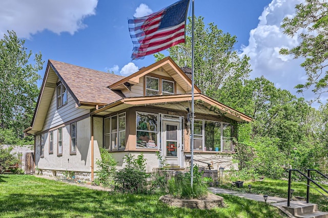 1107 Edmund Ave, Saint Paul, MN 55104 - view of front of home with roof with shingles, a sunroom, a front lawn, and stucco siding