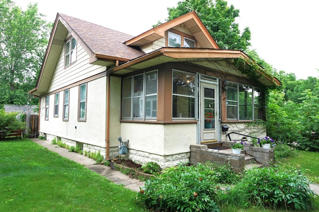 1107 Edmund Ave, Saint Paul, MN 55104 - view of side of home featuring roof with shingles, a sunroom, and a lawn