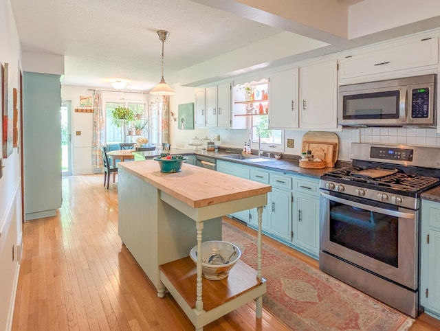 3466 Yukon Ave N, New Hope, MN 55427 - kitchen with stainless steel appliances, wooden counters, blue cabinetry, light wood-type flooring, and decorative light fixtures