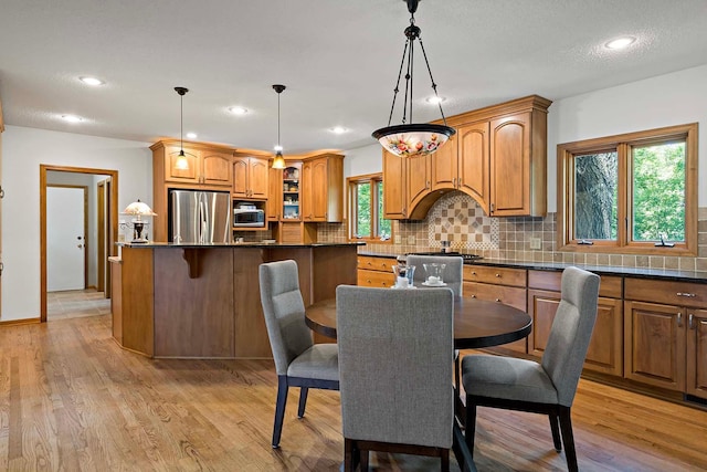 13545 Glasgow Ln, Apple Valley, MN 55124 - kitchen featuring appliances with stainless steel finishes, dark countertops, backsplash, a kitchen breakfast bar, and light wood-type flooring