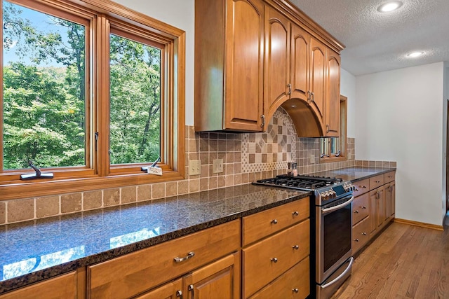 13545 Glasgow Ln, Apple Valley, MN 55124 - kitchen with stainless steel gas stove, a textured ceiling, healthy amount of natural light, light wood-type flooring, and dark stone counters