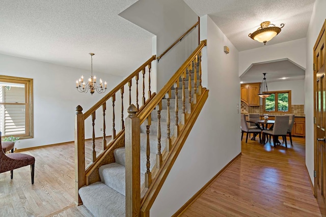 13545 Glasgow Ln, Apple Valley, MN 55124 - stairs featuring a textured ceiling, wood finished floors, a chandelier, and baseboards