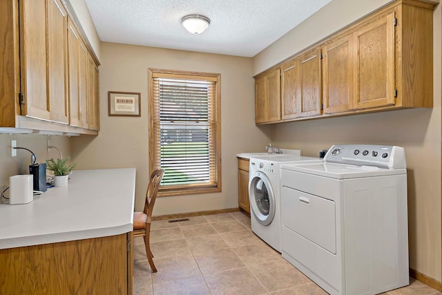 13545 Glasgow Ln, Apple Valley, MN 55124 - laundry area featuring washing machine and dryer, cabinet space, baseboards, a textured ceiling, and light tile patterned flooring