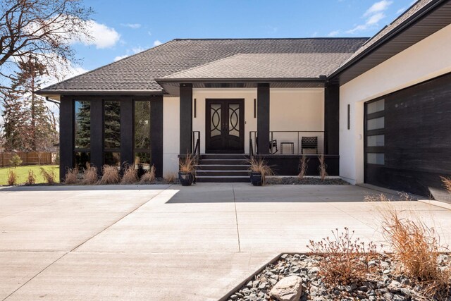 16216 Gleason Lake Rd, Minnetonka, MN 55391 - view of exterior entry featuring stucco siding, covered porch, an attached garage, roof with shingles, and driveway