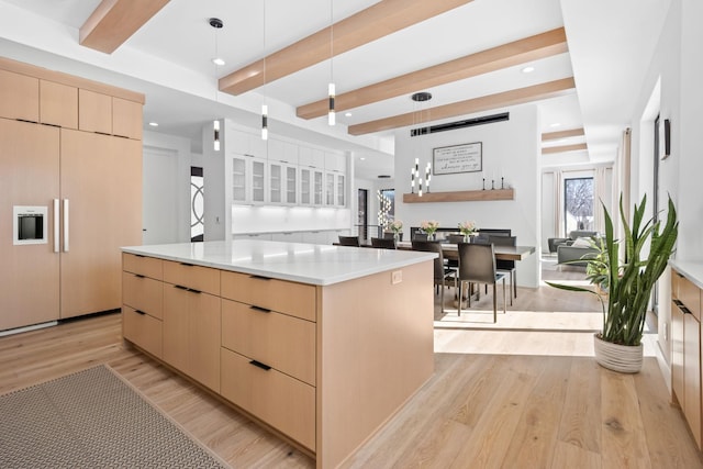 16216 Gleason Lake Rd, Minnetonka, MN 55391 - kitchen featuring light brown cabinetry, modern cabinets, beam ceiling, light wood-style flooring, and a large island