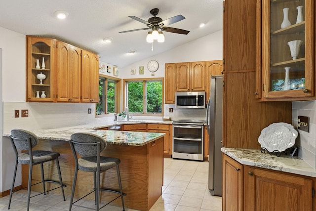 1378 Dunsmore Dr, Waconia, MN 55387 - kitchen featuring appliances with stainless steel finishes, a peninsula, a sink, vaulted ceiling, and tasteful backsplash