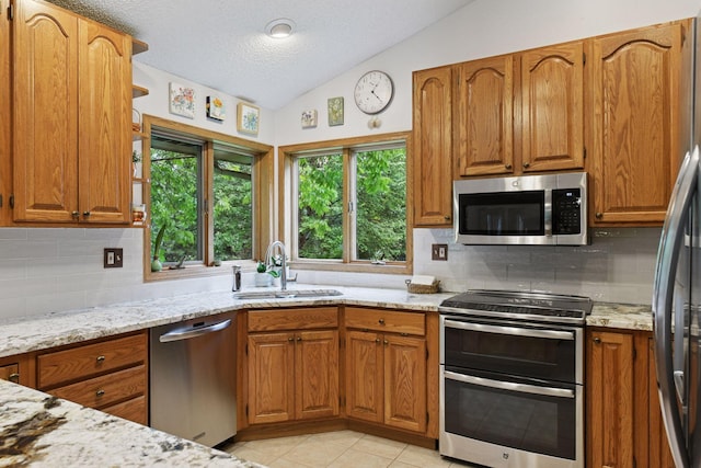 1378 Dunsmore Dr, Waconia, MN 55387 - kitchen featuring stainless steel appliances, lofted ceiling, a sink, brown cabinets, and backsplash