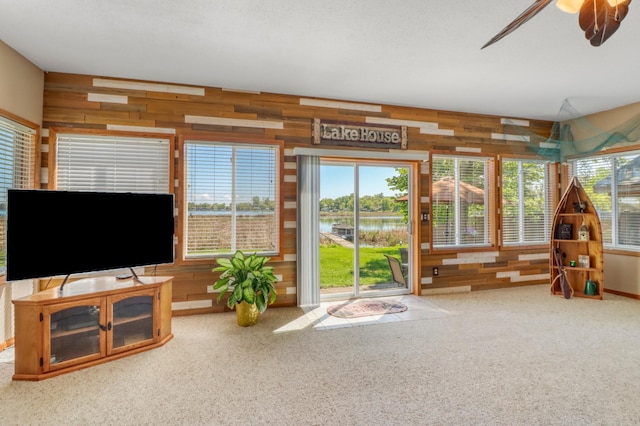 25934 Brolin Beach Rd, Detroit Twp, MN 56501 - carpeted living room with wood walls, a water view, and ceiling fan