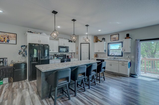 17690 Clayton Ave E, Vermillion Twp, MN 55068 - kitchen with black appliances, a kitchen island, light wood-type flooring, white cabinetry, and recessed lighting