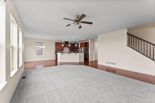 14111 Abercorn Ave, Rosemount, MN 55068 - living area with dark colored carpet, ceiling fan, a chandelier, baseboards, and stairway