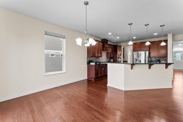 14111 Abercorn Ave, Rosemount, MN 55068 - kitchen featuring appliances with stainless steel finishes, dark countertops, dark wood-style flooring, tasteful backsplash, and a breakfast bar