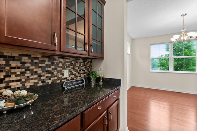 14111 Abercorn Ave, Rosemount, MN 55068 - bar area featuring decorative backsplash, a chandelier, wood finished floors, hanging light fixtures, and baseboards